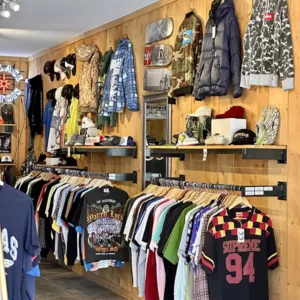Wooden panel wall of vintage men's jackets and tees with caps and shoes.