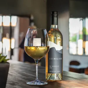 Los Milics white wine bottle and wine glass on a bar counter.