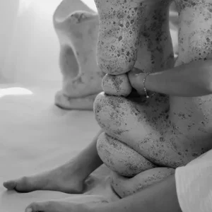 Slumped organic clay sculptural form embraced by a figure.